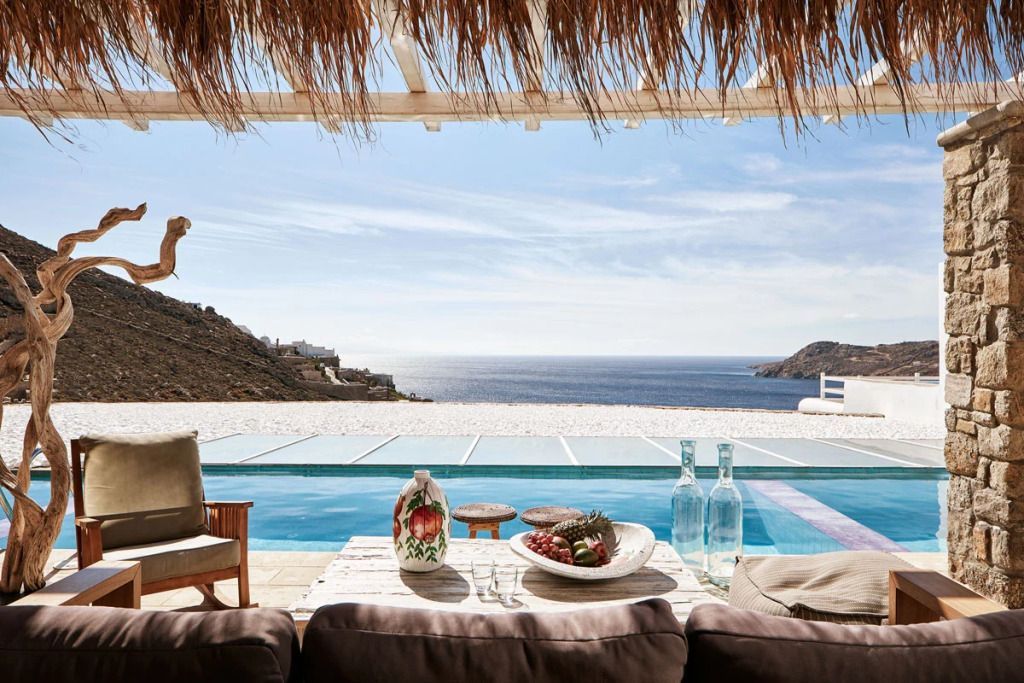 Veranda mit Blick auf Pool und Meer, dekoriert mit Speisen und eleganten Flaschen