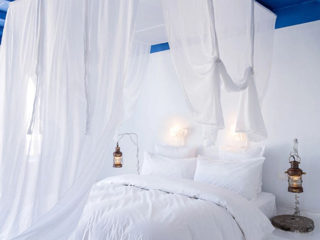 Helles Schlafzimmer mit weißen Vorhängen und Bettwäsche im Mykonos Blu Resort