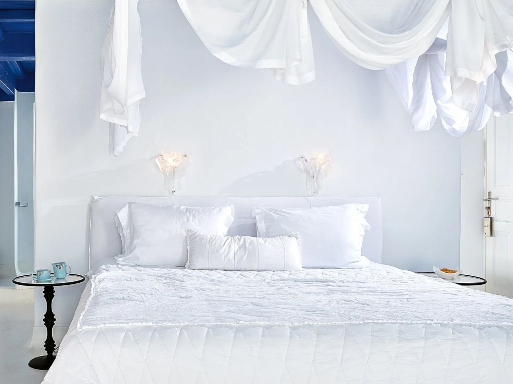Großes weißes Doppelbett mit luxuriösen Kissen und Dekoration im Mykonos Blu Resort