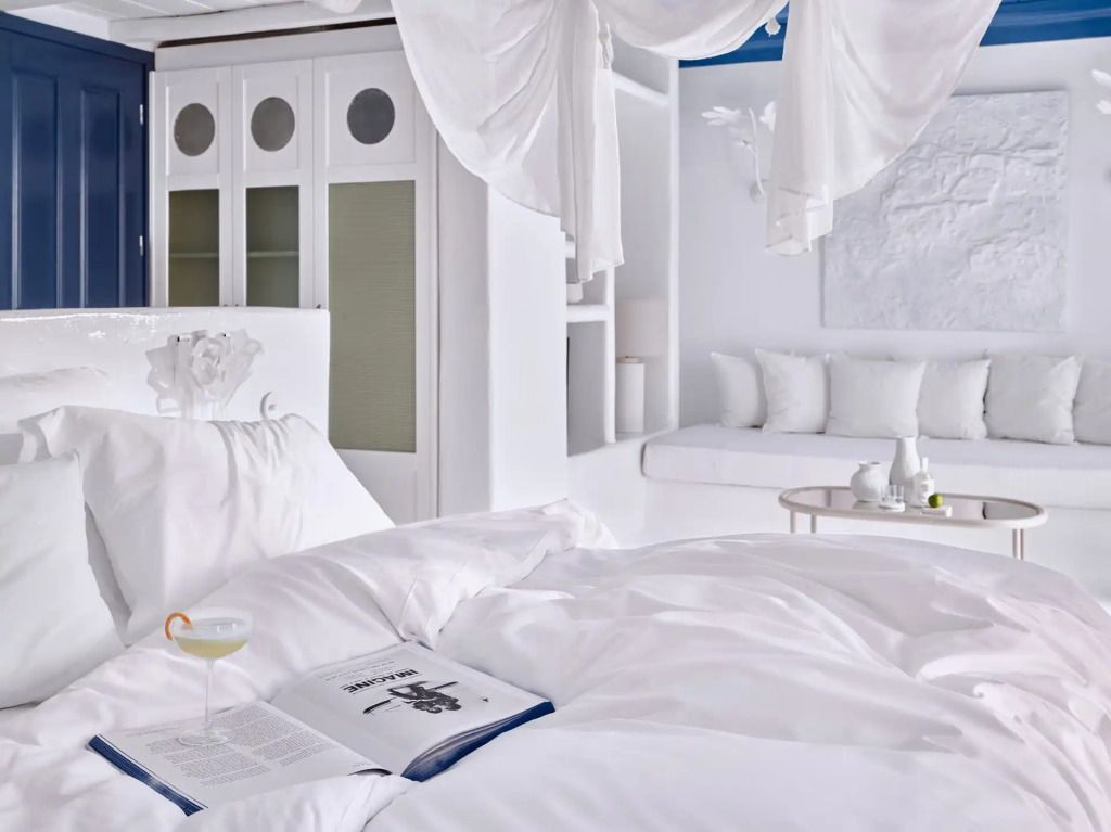 Gemütliches Bett in der Cobalt Blu Villa mit Zeitschrift und Cocktail.