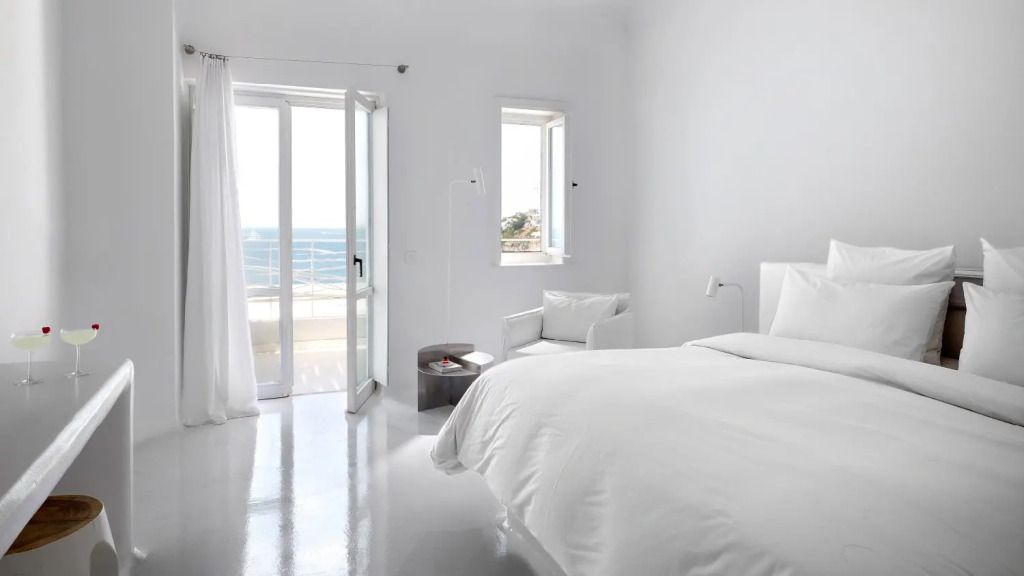 Helles Schlafzimmer mit Doppelbett und Meerblick-Balkon im Mykonos Blu Resort
