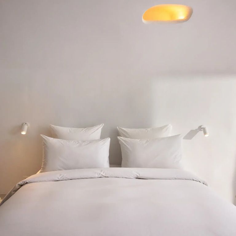 Weißes Doppelbett mit modernen Wandleuchten in einem edlen Bungalow