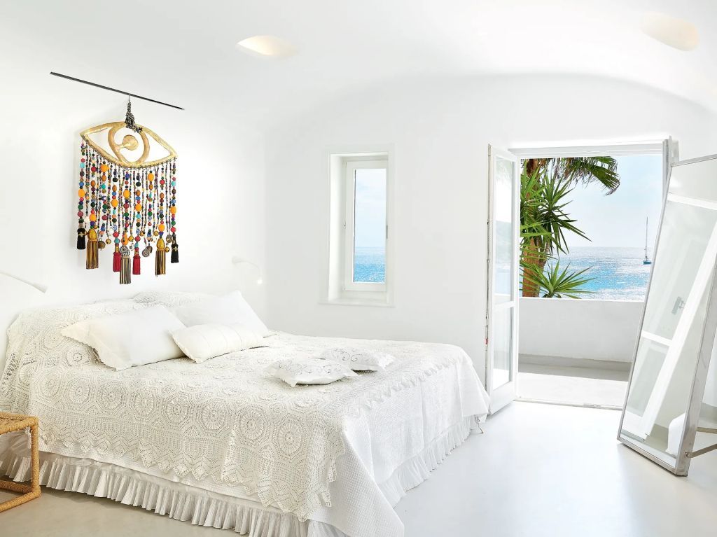 Helles Schlafzimmer mit Doppelbett und Meerblick auf Balkon
