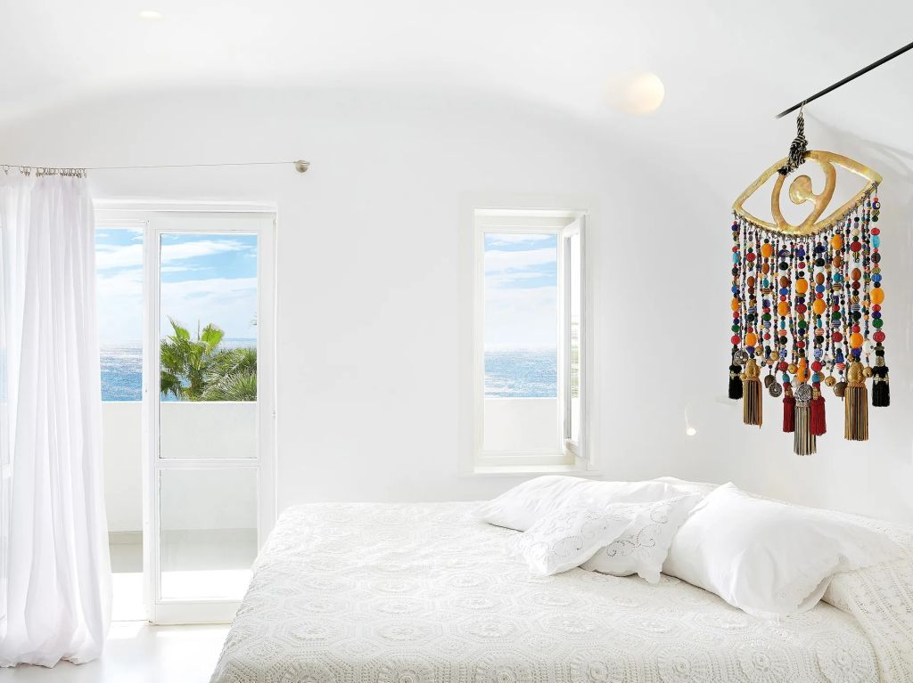 Strahlend weißes Zimmer mit Meerblick und kunstvoller Dekoration