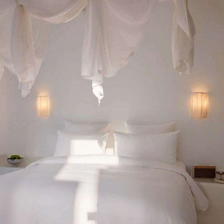 Doppelbett mit weißen Vorhängen und Wandleuchten