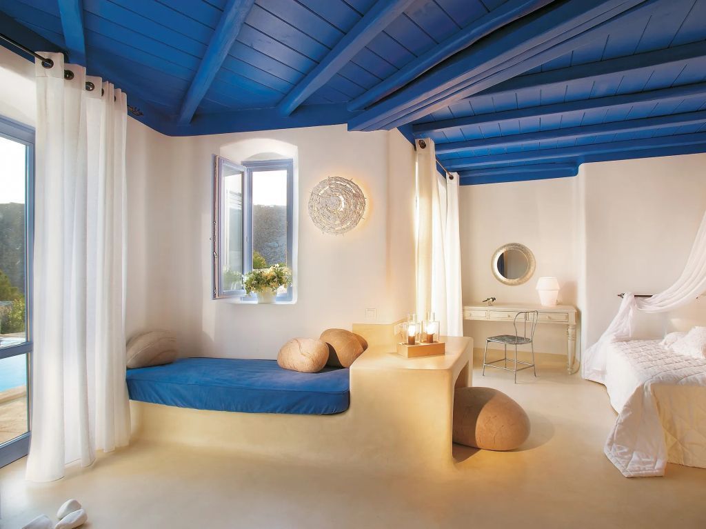 Geräumiges Zimmer mit blauem Fensterrahmen. Kombination aus Sitzecke und Schreibtisch.