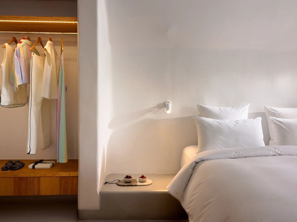 Schlafzimmeransicht mit Bett, offener Kleiderablage und stilvollen Details.