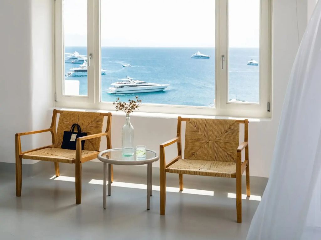 Sitzbereich mit großen Fenstern und Blick auf das Meer mit Yachten
