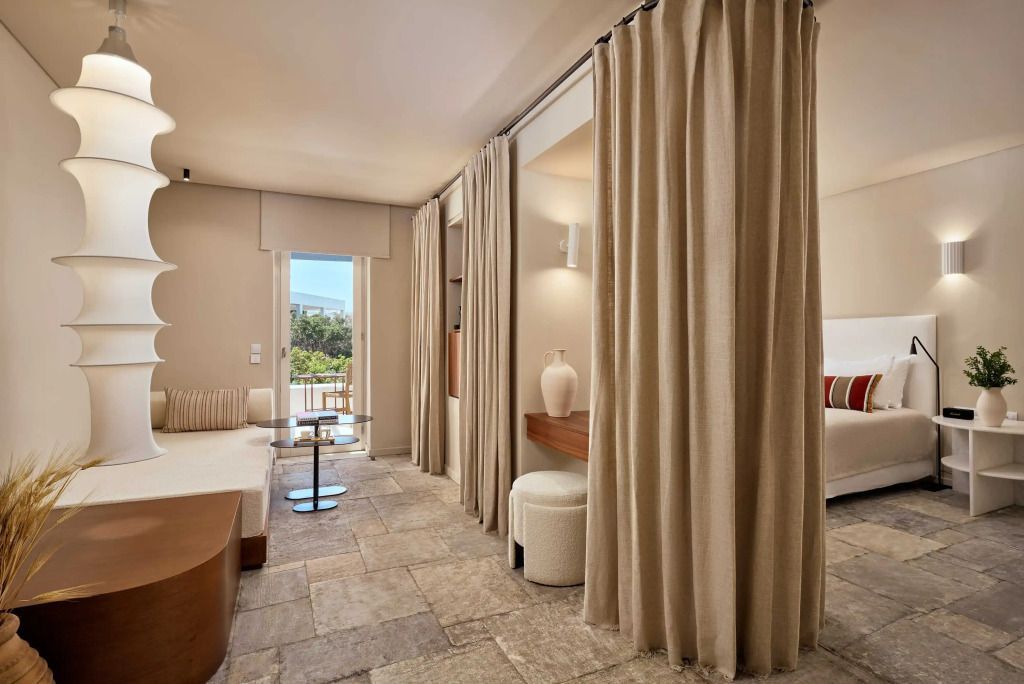 Helles Wohnzimmer der Deluxe Suite mit Gardinen und Gartenausblick