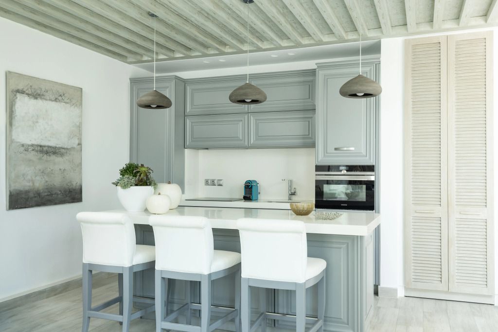 Moderne Küche mit grauem Schrank, Barhockern und Kaffeemaschine in einer Villa.