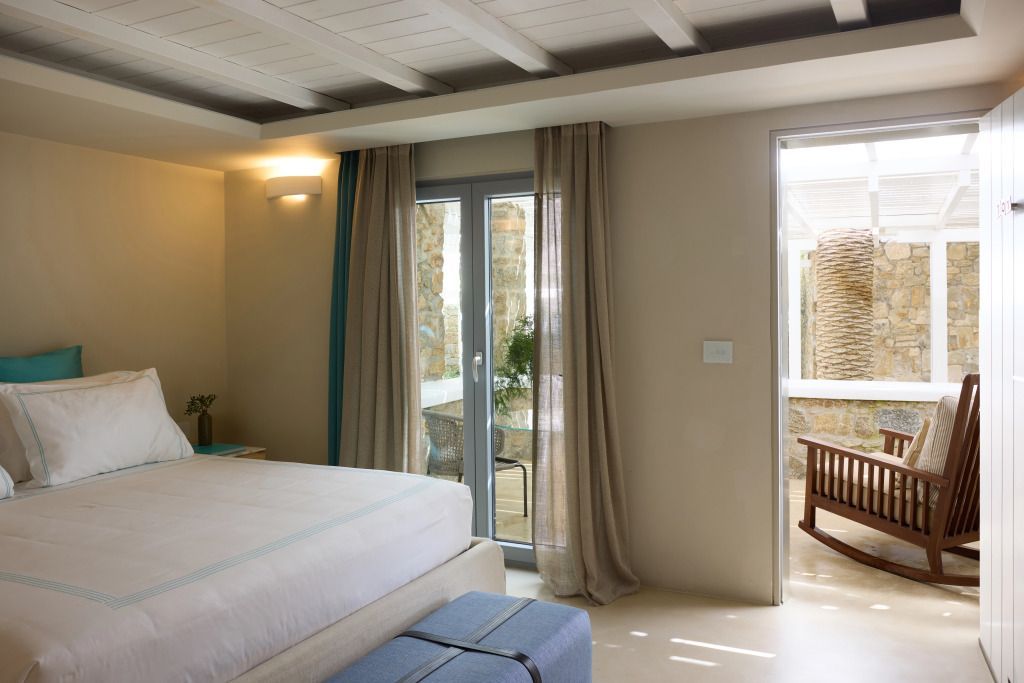 Helles Schlafzimmer mit Zugang zur Terrasse und stilvollen Vorhängen.