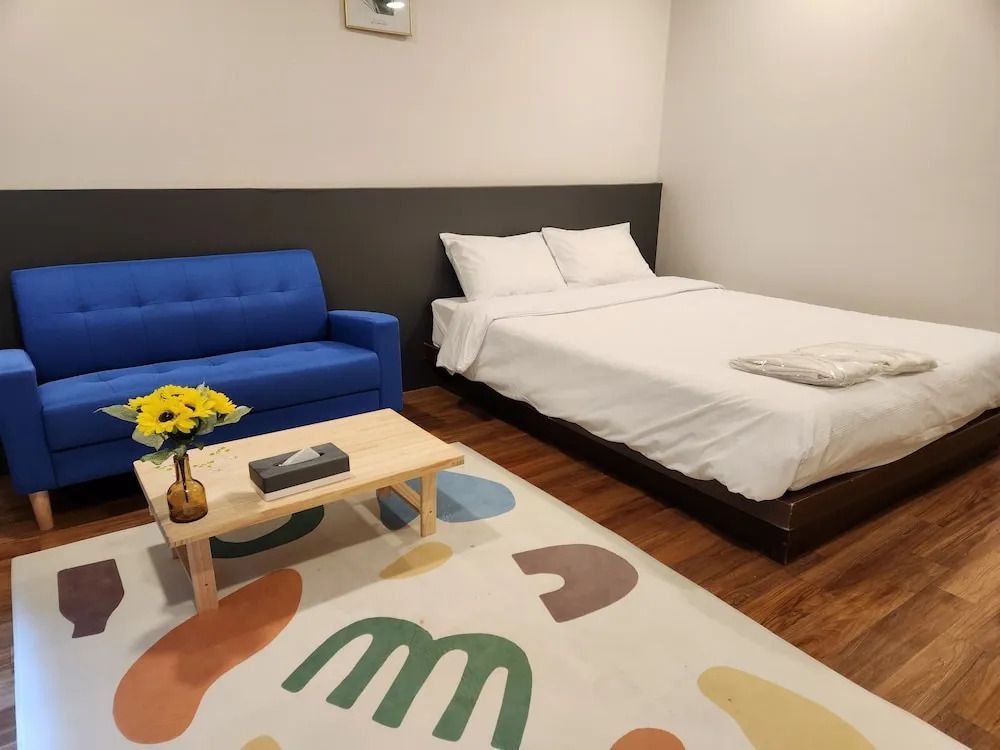 Hotelzimmer mit blauer Couch, Tisch mit Blumen und Doppelbett.