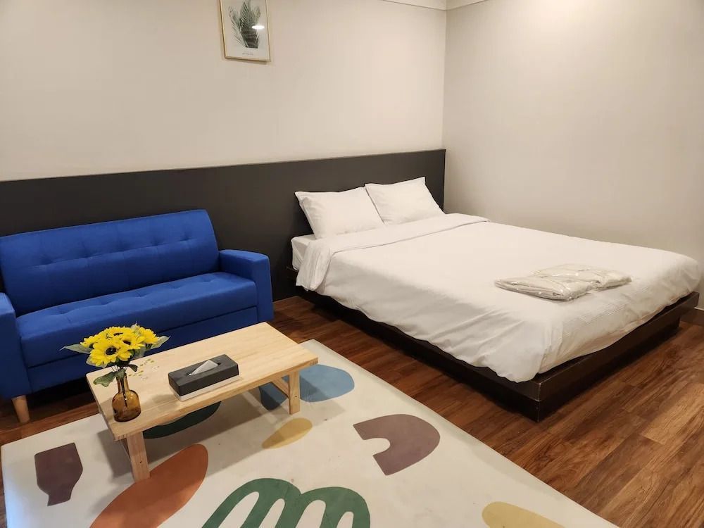 Harmonische Einrichtung mit Doppelbett, blauer Couch und buntem Teppich.