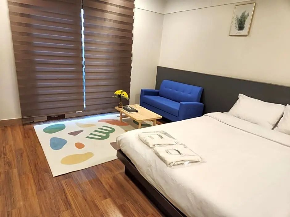 Superior Doppelzimmer mit Doppelbett, blauer Couch und Holzboden.