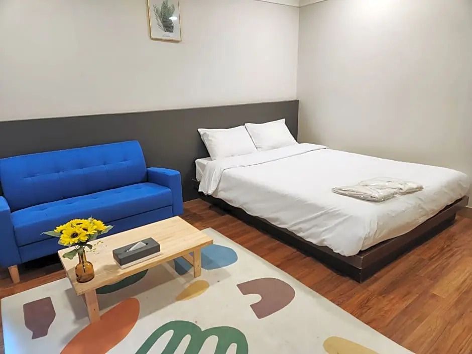 Gemütliches Superior Doppelzimmer mit blauem Sofa und farbigem Teppich.