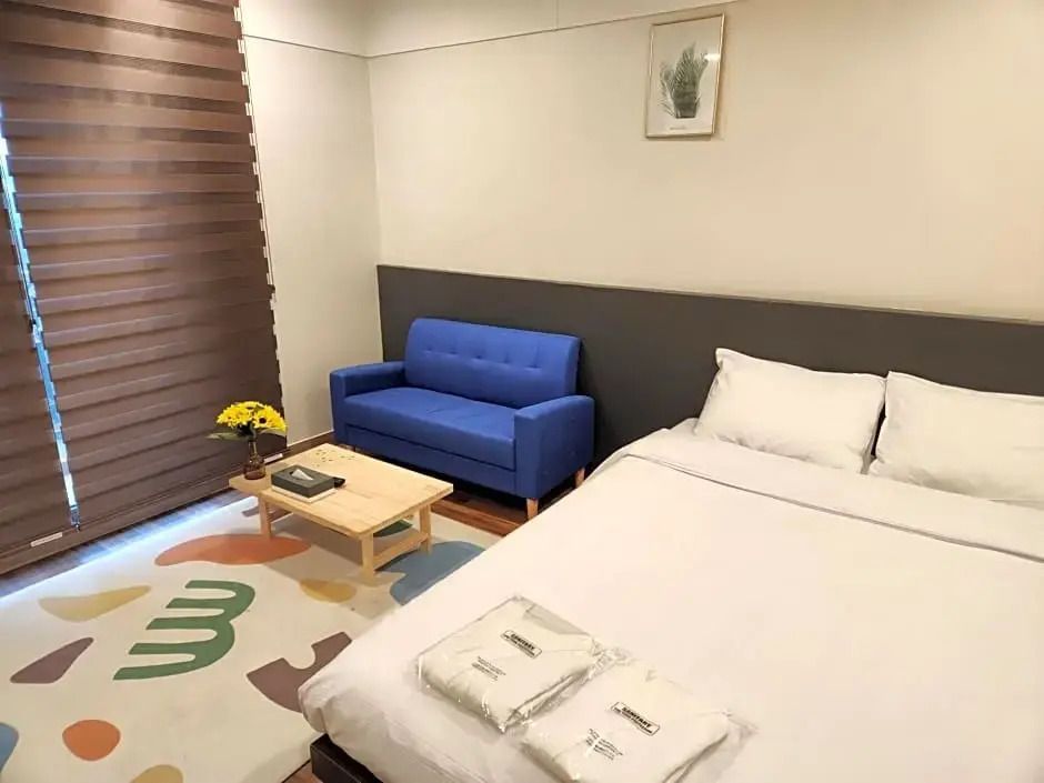 Helles Hotelzimmer mit Doppelbett und blauer Couch.