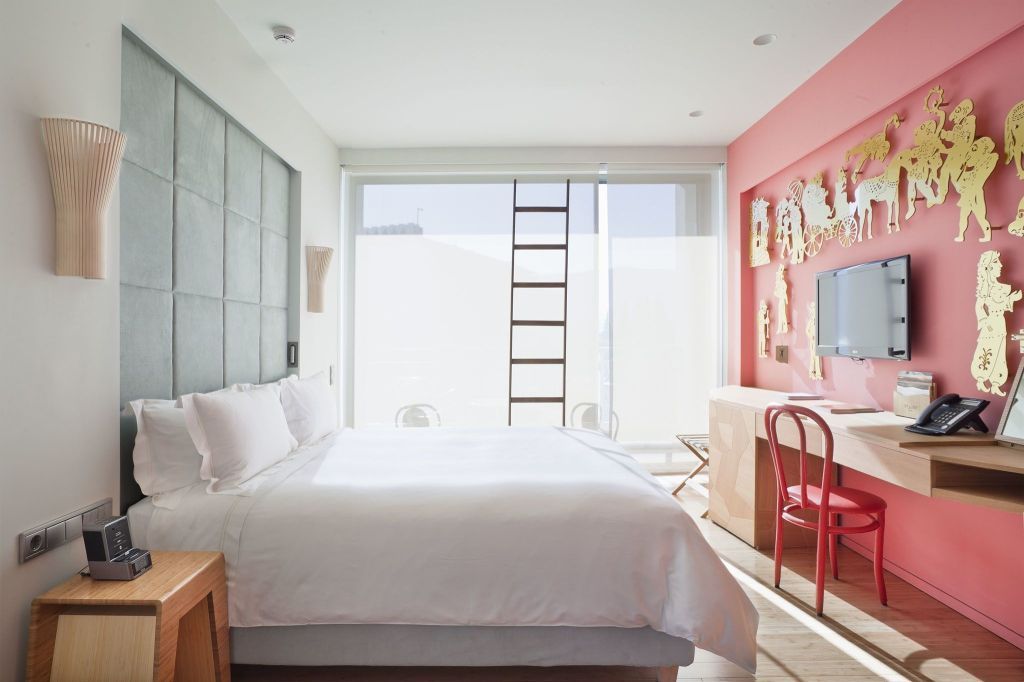 Helles Zimmer mit Doppelbett, modernem Schreibtisch und großem Fenster zum Balkon.