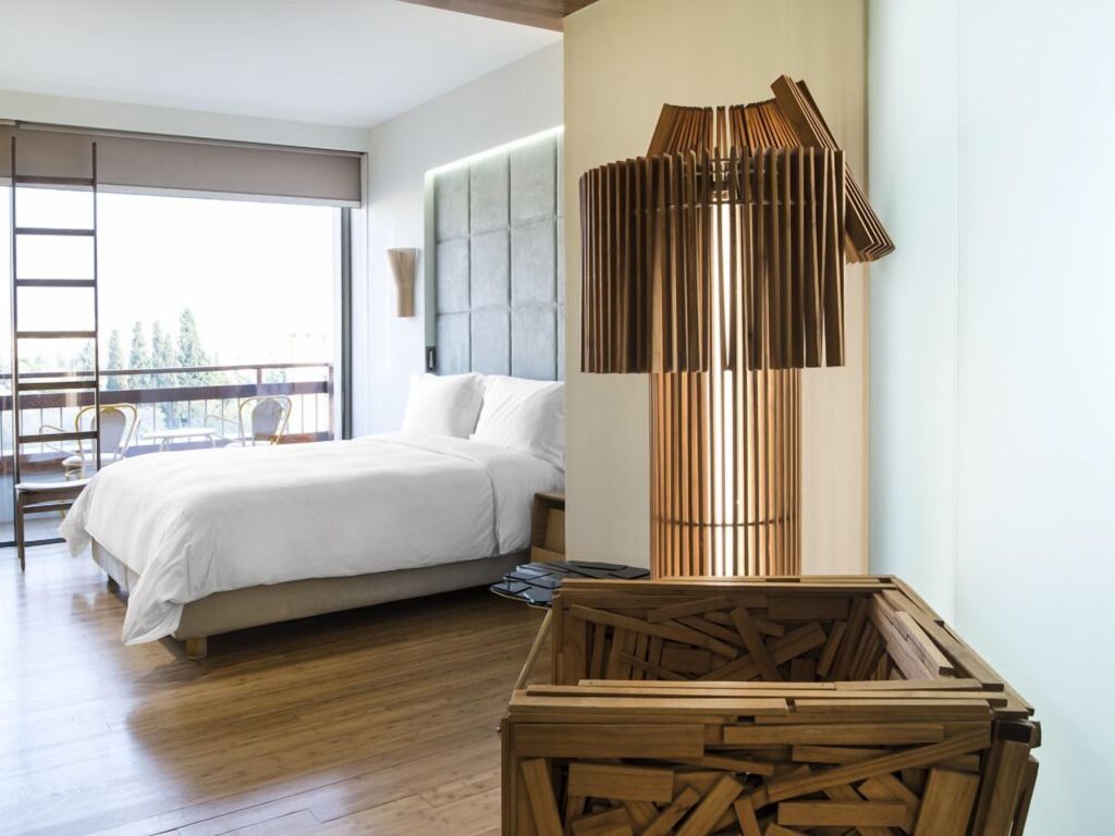 Modernes Doppelzimmer mit hölzernem Lampen- und Raumteilerdesign, Balkonzugang.