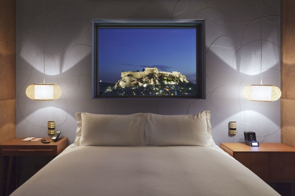 Doppelbett mit nächtlichem Stadtblick auf eine beleuchtete historische Festung.