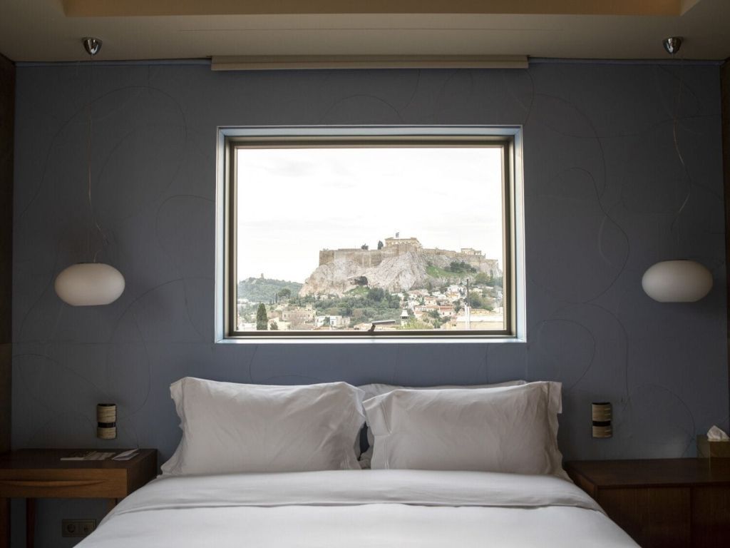 Helles Schlafzimmer mit Fensterblick auf eine historische Festung bei Tageslicht.