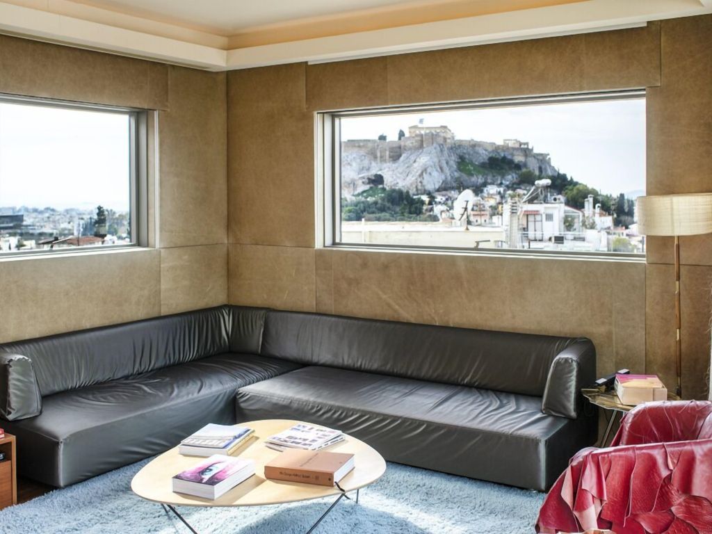 Ecksofa mit Blick auf die historische Stadt und Bücher auf einem runden Tisch.