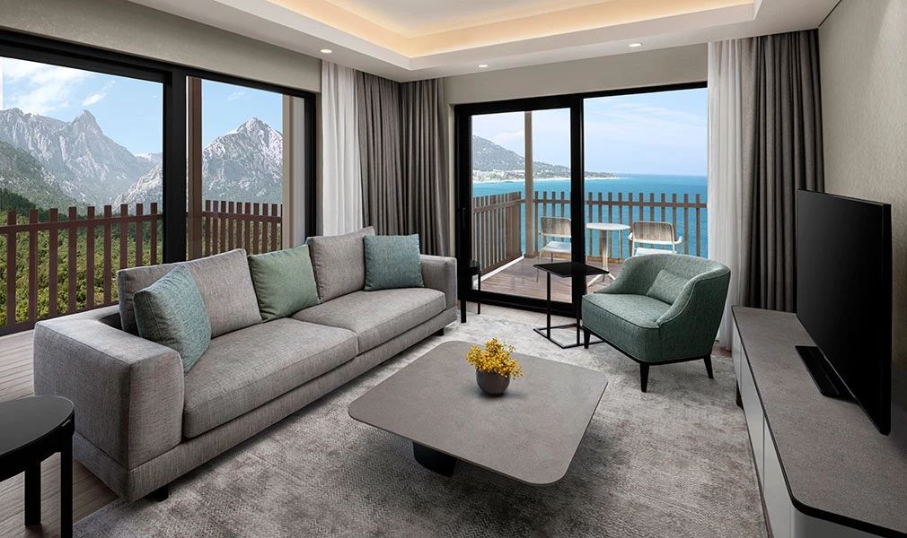 Wohnbereich der Corner Suite mit Panoramablick auf das Meer und die Berge.