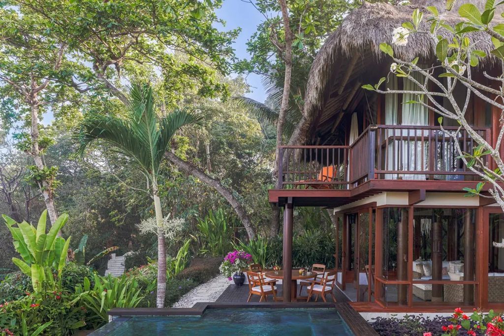Villa mit privatem Garten und Pool, umgeben von tropischer Vegetation.