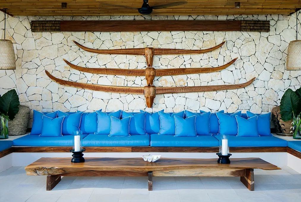 Gemütliche Lounge mit blauer Couch und Wanddekoration aus Holz.