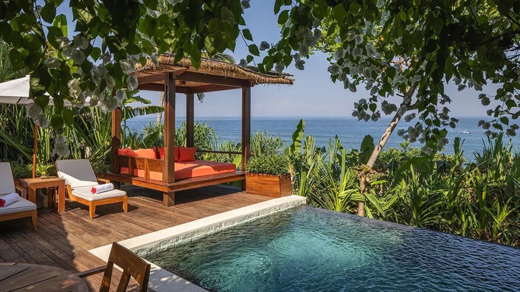 Infinity Pool mit Meerblick umgeben von tropischer Vegetation