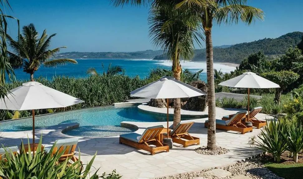 Atemberaubender Meerblick vom Infinity-Pool mit Sonnenliegen und Palmen