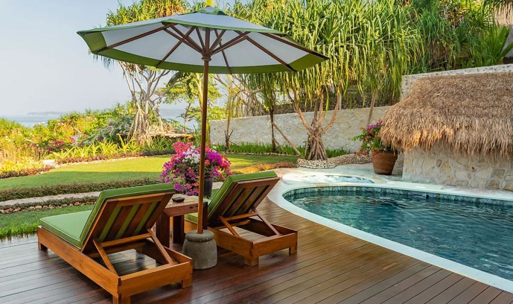 Private Terrasse mit Liegestühlen und Pool in tropischer Gartenanlage