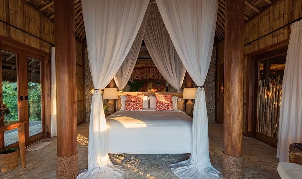 Luxuriöses Doppelbett mit Baldachin in tropischer Villa, warme Holzakzente