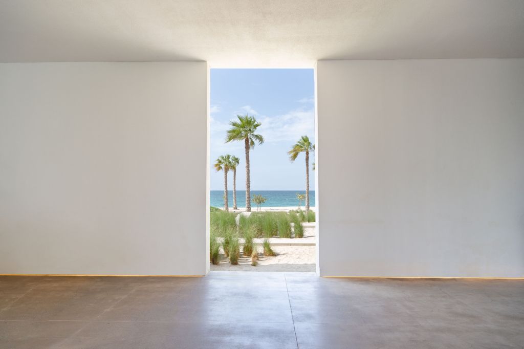 Ausblick auf das Meer durch moderne Architektur mit Palmen im Vordergrund.