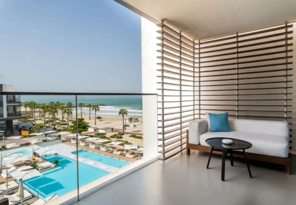 Balkon mit Sitzgelegenheiten und Meerblick über den Pool und Strand