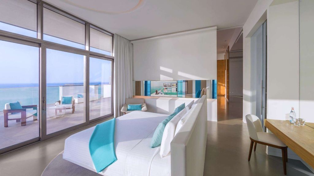 Helles Schlafzimmer mit Meerblick Balkontüren, weißen Möbeln und türkisfarbenen Akzenten