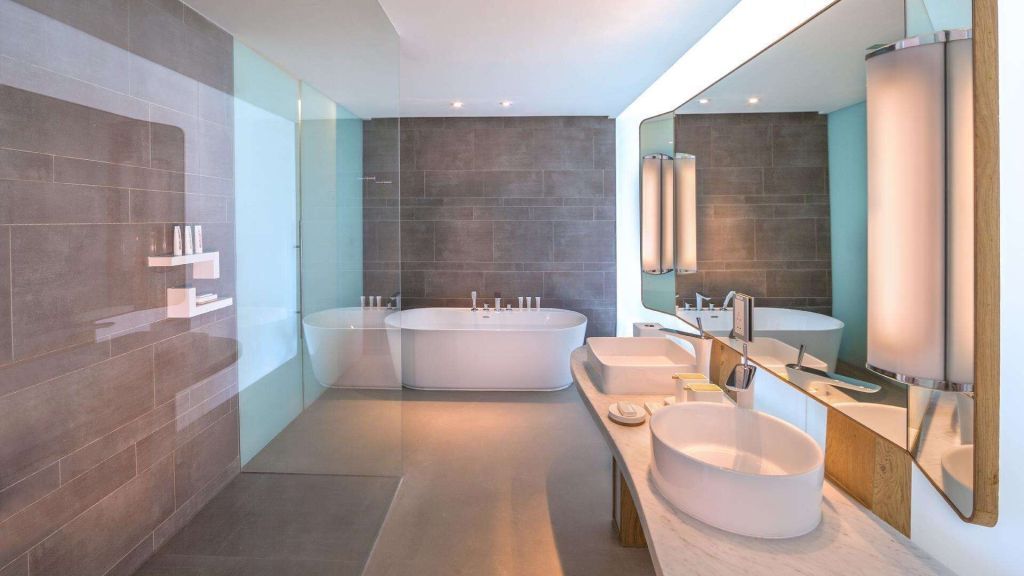 Großzügiges Badezimmer mit moderner Badewanne, Doppelwaschbecken und großen Spiegeln
