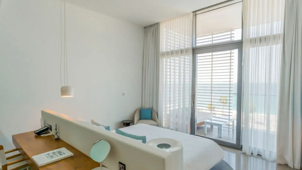 Schlafzimmer mit Blick auf den Balkon und das Meer durch bodentiefe Fenster