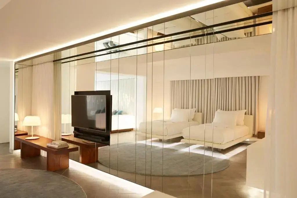 Großzügiges Zimmer mit zwei Doppelbetten und moderner Glaswand