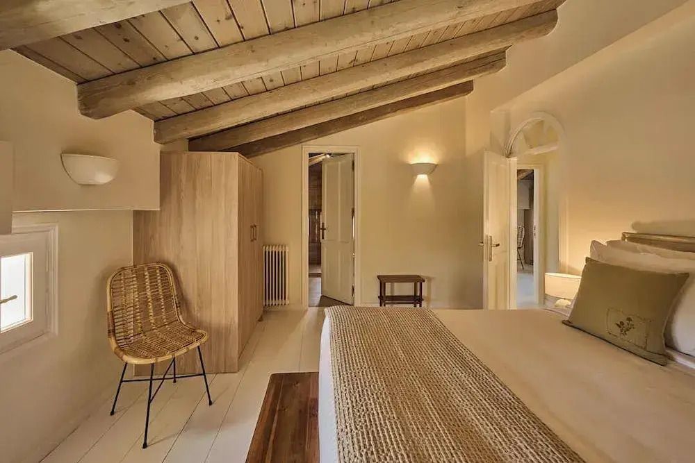 Schlafzimmer mit sichtbaren Holzbalken und sanfter Beleuchtung für ein warmes Ambiente.