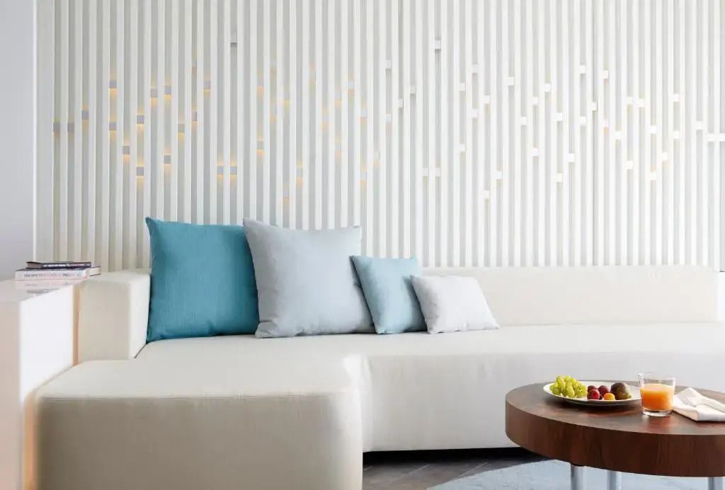 Luxuriöse Suite mit moderner, weißer Couch und blauen Kissen.