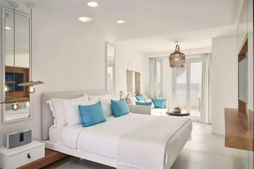 Lichtdurchflutetes Zimmer mit Doppelbett und blauen Akzenten, Balkonzugang