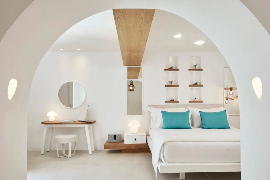 Helles Schlafzimmer mit Doppelbett, türkisfarbenen Kissen und modernem Dekor