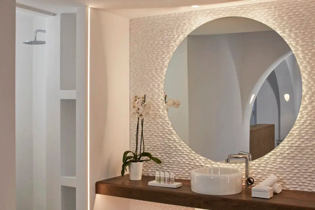 Moderne Badezimmer-Einrichtung mit rundem Spiegel und Waschbecken auf Holzablage