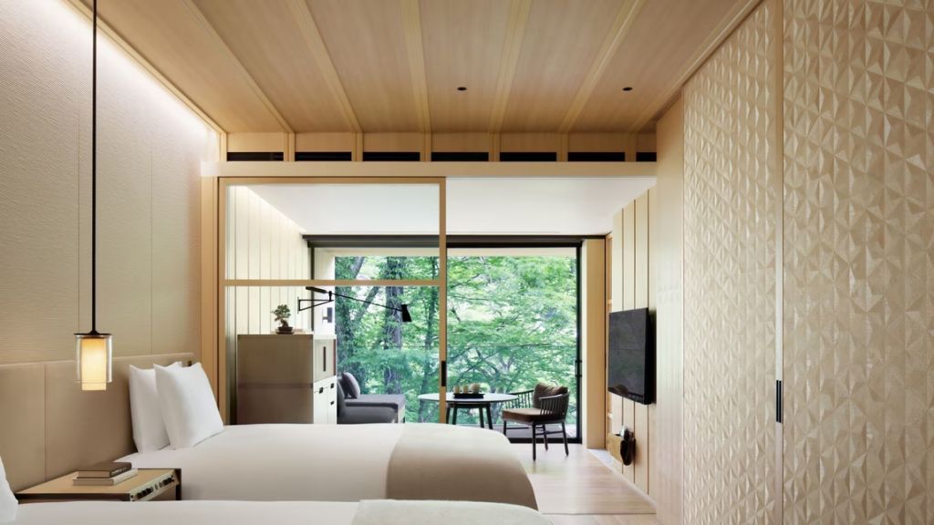 Modernes Gästezimmer mit zwei Einzelbetten und Bergblick durch ein großes Fenster