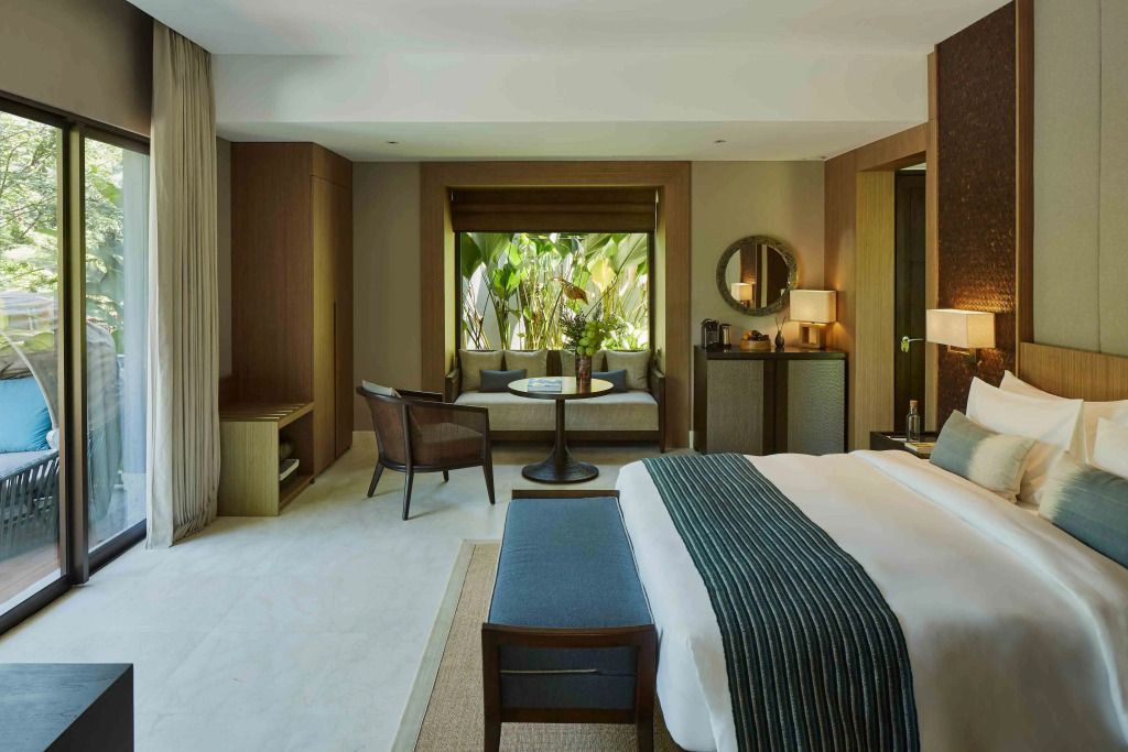 Elegantes Standardzimmer mit Doppelbett und gemütlicher Sitzecke vor tropischen Pflanzen