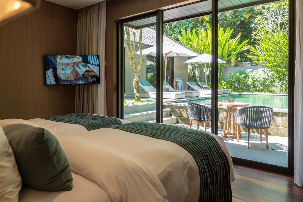 Schlafzimmer mit Blick auf Pool und Garten durch große Fenster.