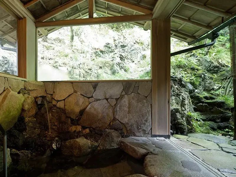 Traditionelles japanisches Onsen mit Felsen und Blick auf die Natur.