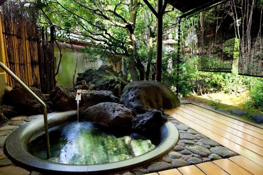 Onsen-Bereich mit Natursteinen und üppiger Vegetation