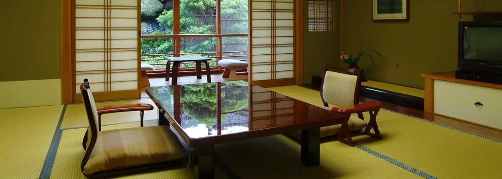Traditionelles japanisches Zimmer mit Tatami und großem Holztisch mit Gartenblick