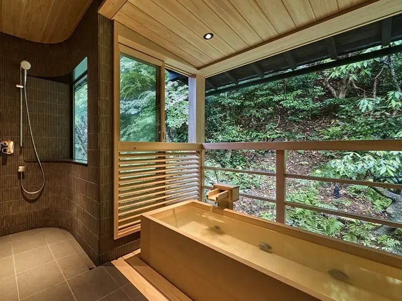 Offenes Badezimmer mit japanischem Holzbad und Waldsicht